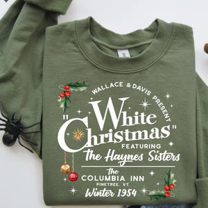May include: A green sweatshirt with a white graphic print that reads "Wallace & Davis Present "White Christmas" Featuring The Haynes Sisters The Columbia Inn Pinetree, VT Winter 1954".