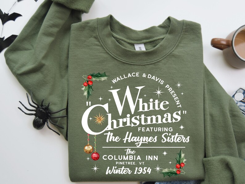 May include: A green sweatshirt with a white graphic print that reads "Wallace & Davis Present "White Christmas" Featuring The Haynes Sisters The Columbia Inn Pinetree, VT Winter 1954".