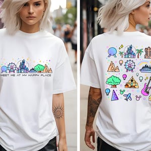 Op de afbeelding: Wit T-shirt met een kleurrijke afbeelding van Disney World-bezienswaardigheden en de tekst "Meet me at my happy place" op de voorkant. De achterkant van het shirt heeft een kleurrijk patroon van Disney World-iconen.