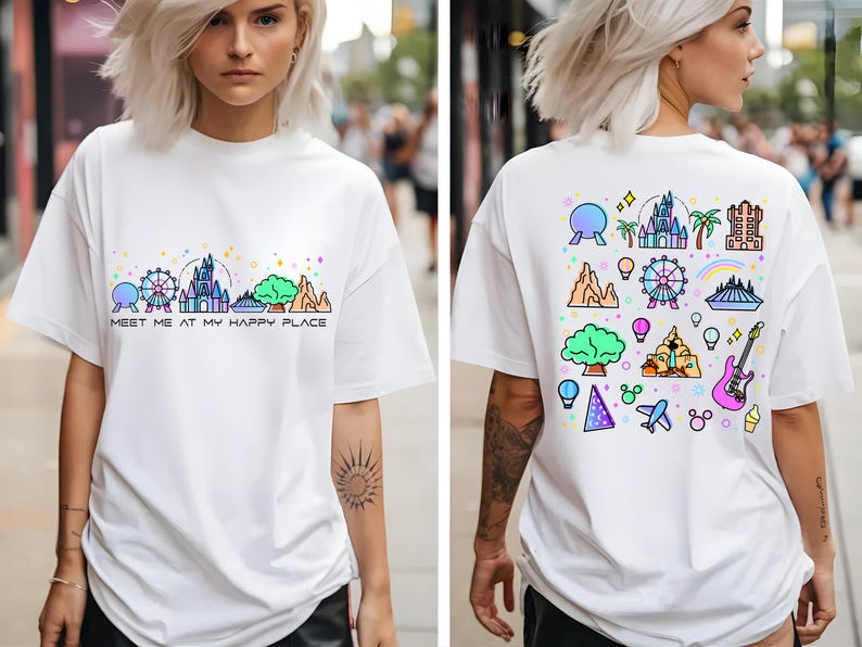 Op de afbeelding: Wit T-shirt met een kleurrijke afbeelding van Disney World-bezienswaardigheden en de tekst "Meet me at my happy place" op de voorkant. De achterkant van het shirt heeft een kleurrijk patroon van Disney World-iconen.