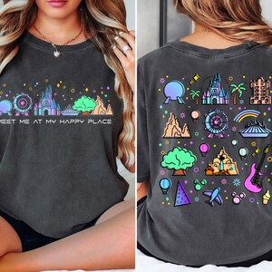 Op de afbeelding: Een donkergrijs T-shirt met een kleurrijke grafische print van verschillende Disney-parkiconen en de tekst "Meet me at my happy place".