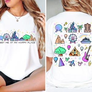 Op de afbeelding: Wit T-shirt met een kleurrijke afbeelding van Disney World-bezienswaardigheden aan de voor- en achterkant. De afbeelding aan de voorkant zegt "Meet me at my happy place".