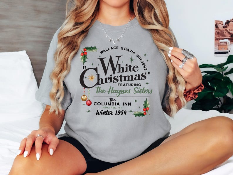 May include: Gray t-shirt with a vintage-style graphic design featuring the text "Wallace & Davis Present "White Christmas" Featuring The Haynes Sisters The Columbia Inn Pinetree VT Winter 1954".