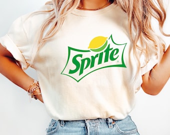 Op de afbeelding: Een wit T-shirt met een groen en geel Sprite-logo. Het logo toont het woord "Sprite" in groene letters met een gele citroenschijf.