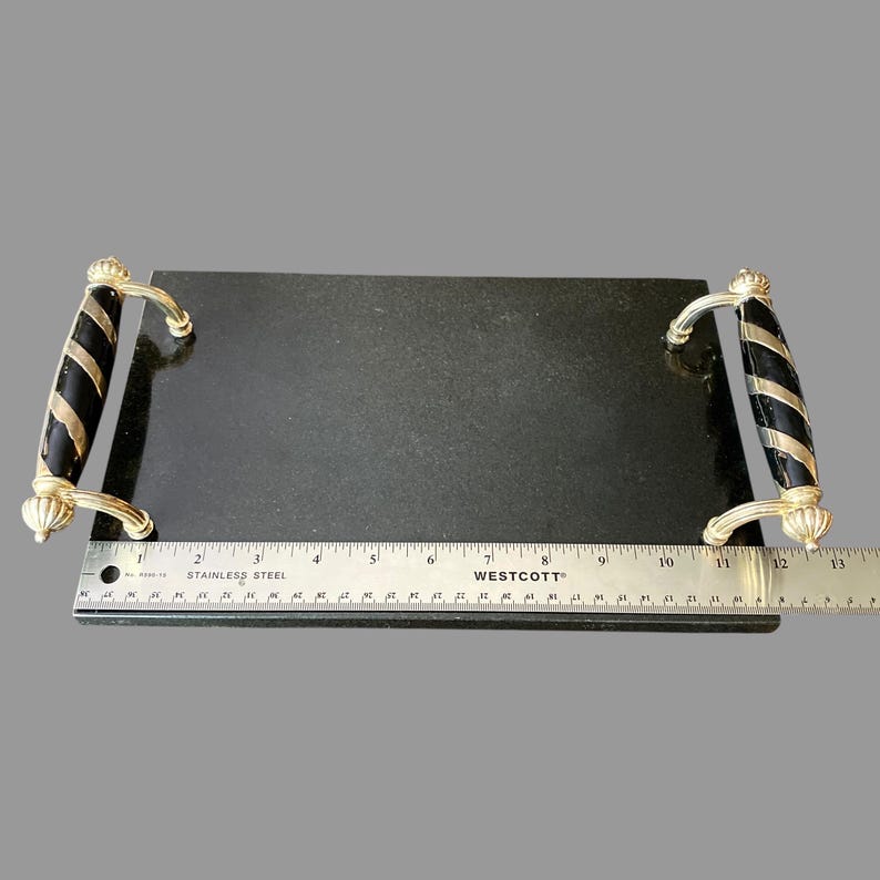 May include: A rectangular black serving tray with gold-coloured handles featuring black and gold striped accents. The tray is shown with a stainless steel ruler, measuring approximately 33 cm in length.