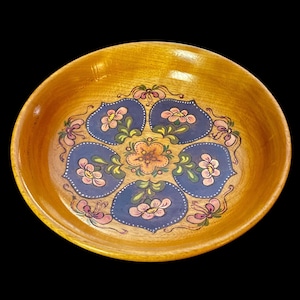 May include: Wooden bowl with a light brown finish and a floral design. The interior features a central orange flower surrounded by six blue petal-shaped designs, each with pink and white flowers.