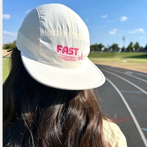May include: White mesh and nylon baseball cap with a pink "FAST is life" logo.