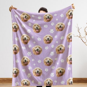 May include: A purple fleece blanket with a repeating pattern of a golden retriever dog's face and white paw prints.
