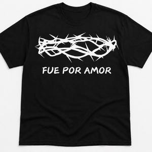 May include: Black t-shirt with a white crown of thorns graphic and the Spanish text "FUE POR AMOR". The design is printed on the front. The shirt has a crew neck and short sleeves. The fabric appears to be cotton.