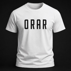 May include: A white short-sleeved t-shirt featuring the word ORAR printed in bold black capital letters across the center of the chest. The garment has a classic crew neckline and a straight hemline, presenting a clean and simple design.
