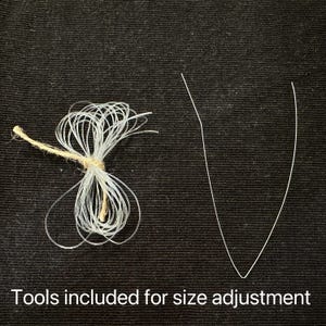 May include: Image shows tools for size adjustment. A bundle of clear, thin, looped cords is tied with twine. A single, thin, V-shaped wire is also present. Text at the bottom reads: Tools included for size adjustment.