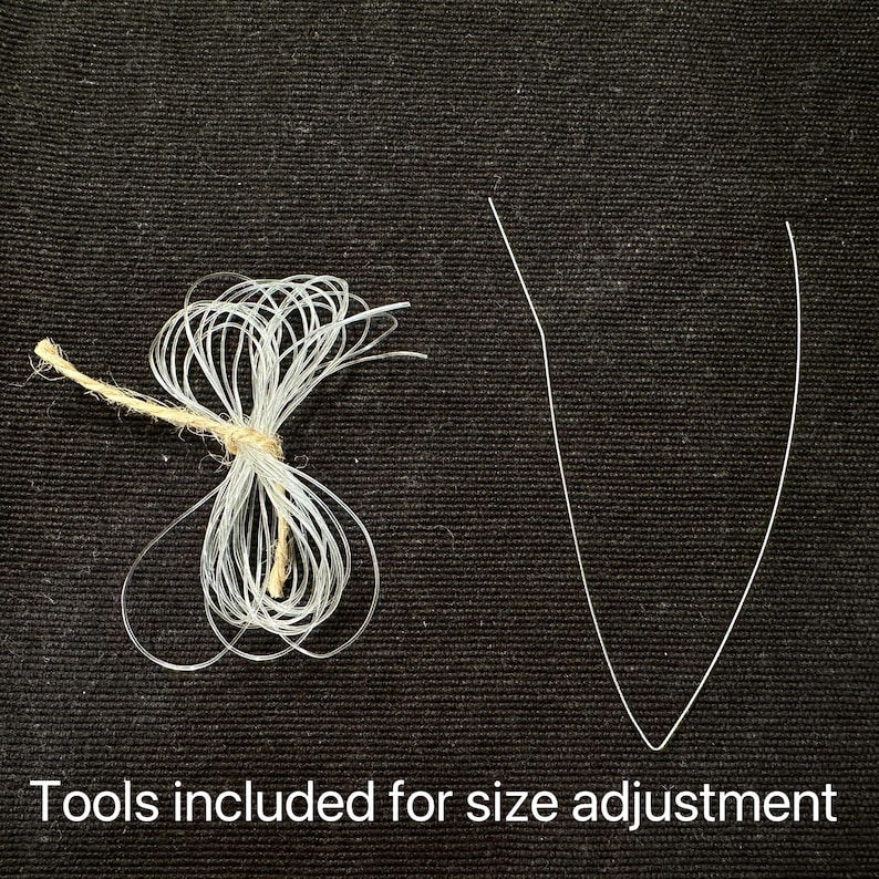 May include: Image shows tools for size adjustment. A bundle of clear, thin, looped cords is tied with twine. A single, thin, V-shaped wire is also present. Text at the bottom reads: Tools included for size adjustment.
