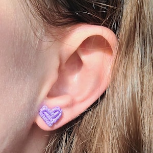 May include: A close-up of a person's ear with a small purple heart-shaped earring.