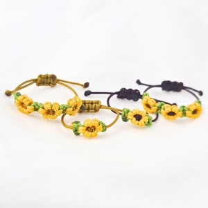 May include: Three handmade friendship bracelets with sunflower designs. The bracelets are made with green, brown, and black string.