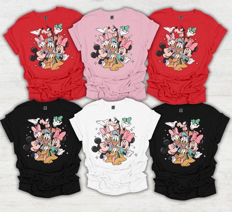 May include: Six t-shirts in various colors: red, pink, black, white. Each shirt features a graphic of Disney characters including Mickey Mouse, Minnie Mouse, Donald Duck, Daisy Duck, Goofy, and Pluto. The design is surrounded by sparkling stars.