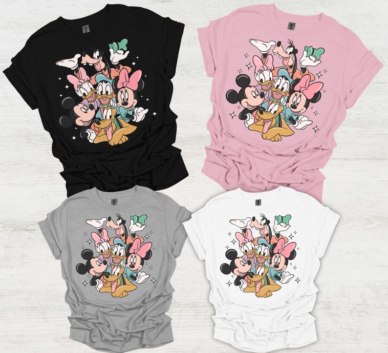May include: Four t-shirts in black, pink, gray, and white, each featuring a colorful graphic of Disney characters including Mickey, Minnie, Donald, Daisy, Goofy, and Pluto. The design is surrounded by small star accents.