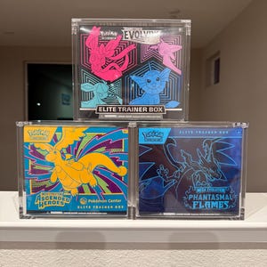 May include: A white ceramic mug with a black handle and the text "But First, Coffee" in a black, bold font. The mug is on a white surface.