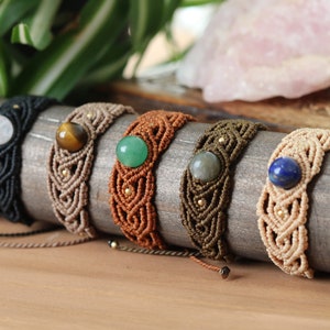 May include: Seven macrame bracelets with different colored cords and gemstone beads. The bracelets are displayed on a wooden surface.