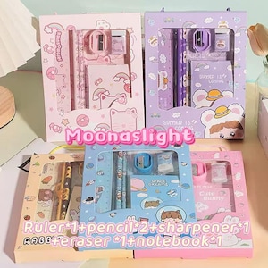 May include: Four stationery sets in pink, purple, blue, and yellow boxes. Each set includes a ruler, pencils, sharpener, eraser, and notebook. The boxes feature illustrations and the text "Moonaslight".