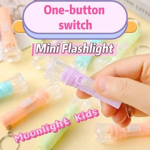 May include: A collection of mini flashlights in pastel shades such as lavender, peach, and mint green. Each flashlight features a clear, textured head and a one-button switch. The text "One-button switch" and "Mini Flashlight" are visible.
