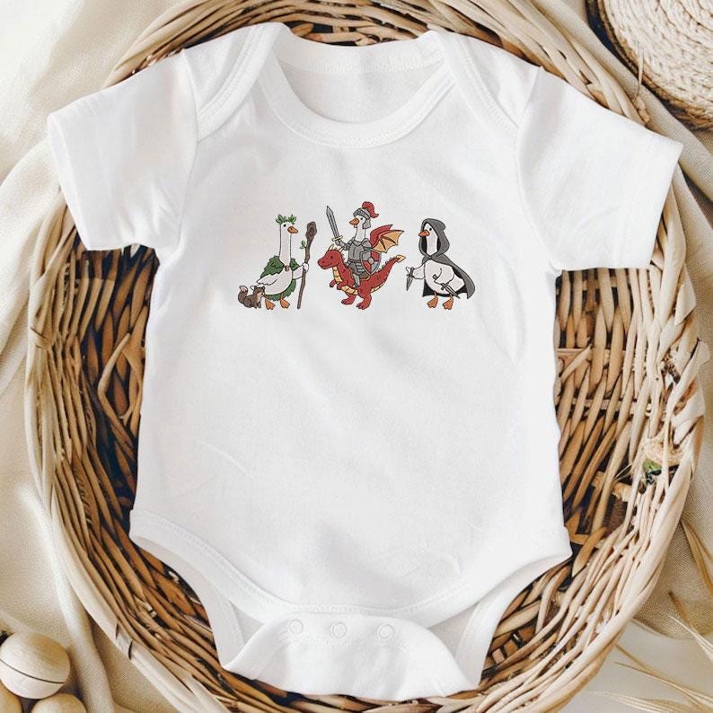 May include: White baby bodysuit with a whimsical embroidered design featuring three cartoon characters: a goose with a staff, a chicken knight riding a red dragon, and a penguin in a cloak. The bodysuit is made of soft fabric.