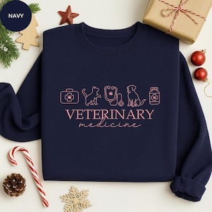 Könnte beinhalten: Eine weiße Keramik-Tasse mit schwarzem Henkel und dem Text "But First, Coffee" in schwarzer, handschriftlicher Schrift. Die Tasse steht auf einer weißen Oberfläche.