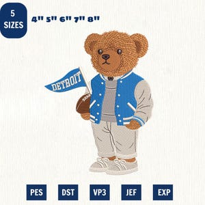 Peut inclure: Un motif de broderie représentant un ours en peluche marron portant une veste universitaire bleue et grise, un pull gris et un pantalon gris. L'ours tient un ballon de football marron et un fanion bleu avec le texte DETROIT. 5 tailles incluses.