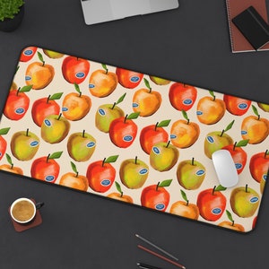 May include: A beige mouse pad with a repeating pattern of red, yellow, and green apples. The apples have a white sticker with the word "Fresh" on them.