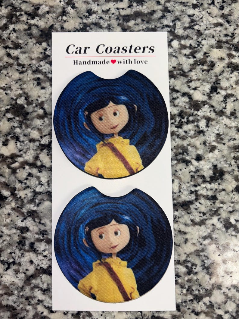 May include: Two round car coasters featuring a graphic of a character with blue hair wearing a yellow raincoat against a dark blue swirling background. The white display card above the coasters reads Car Coasters Handmade with love.