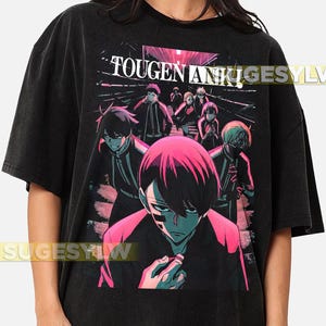 Puede incluir: Camiseta negra con un gráfico vibrante de estilo anime. El diseño muestra un grupo de personajes con acentos rosas y azules, y el texto "TOUGEN AN" es visible en la parte superior. La estética general es una mezcla de tonos oscuros y colores brillantes.