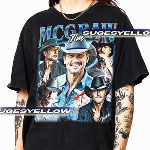 Puede incluir: Camiseta negra con un gráfico de estilo vintage de Tim McGraw. El gráfico presenta varias imágenes de McGraw con un sombrero de vaquero, con el texto "Tim McGraw" y "Sugesyello" impreso en la camiseta.