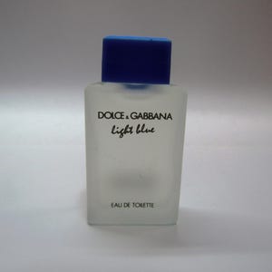 Könnte beinhalten: Eine durchsichtige Glasflasche mit Dolce & Gabbana Light Blue Eau de Toilette. Die Flasche hat einen blauen Verschluss und das Etikett lautet "Dolce & Gabbana Light Blue Eau de Toilette".