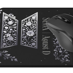 Könnte beinhalten: Schwarze Mauspad mit einem weißen Blumenmuster und dem Text "SUGA | Agust D" in silberner Schrift.