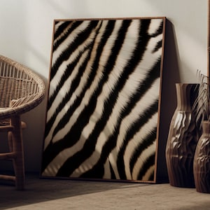 May include: A framed art print featuring a close-up of zebra stripes in black and white. The artwork is displayed on a neutral-colored wall, next to a wicker chair and decorative vases. The print has a wooden frame.
