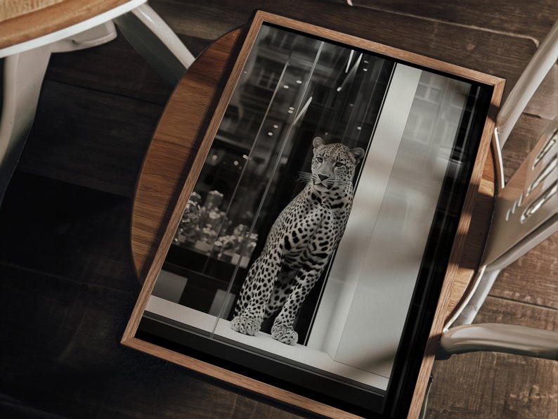 May include: A black and white photograph of a leopard in a window. The leopard is looking at the camera. The photo is framed in a wooden frame.
