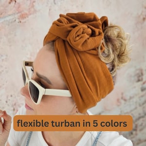 Könnte beinhalten: Ein brauner Turban aus weichem Stoff wird auf dem Kopf getragen. Der Turban ist oben auf dem Kopf zu einem Knoten gebunden. Der Text "flexibler Turban in 5 Farben" ist im Bild sichtbar.