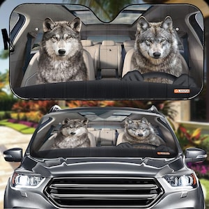 May include: A car sunshade with a black and gray design featuring a wolf's head on each side. The sunshade is installed in a car windshield.