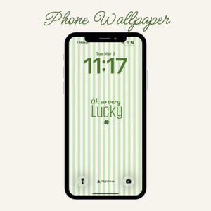 Può includere: Uno smartphone mostra uno sfondo a righe verdi e bianche con la scritta "Oh so very Lucky" e un quadrifoglio. L'ora è 11:17 martedì 3 marzo. Il telefono ha una cornice nera e la scritta "Phone Wallpaper" sopra.