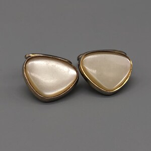May include: A pair of gold-tone cufflinks with a white mother-of-pearl inlay in the shape of a triangle.