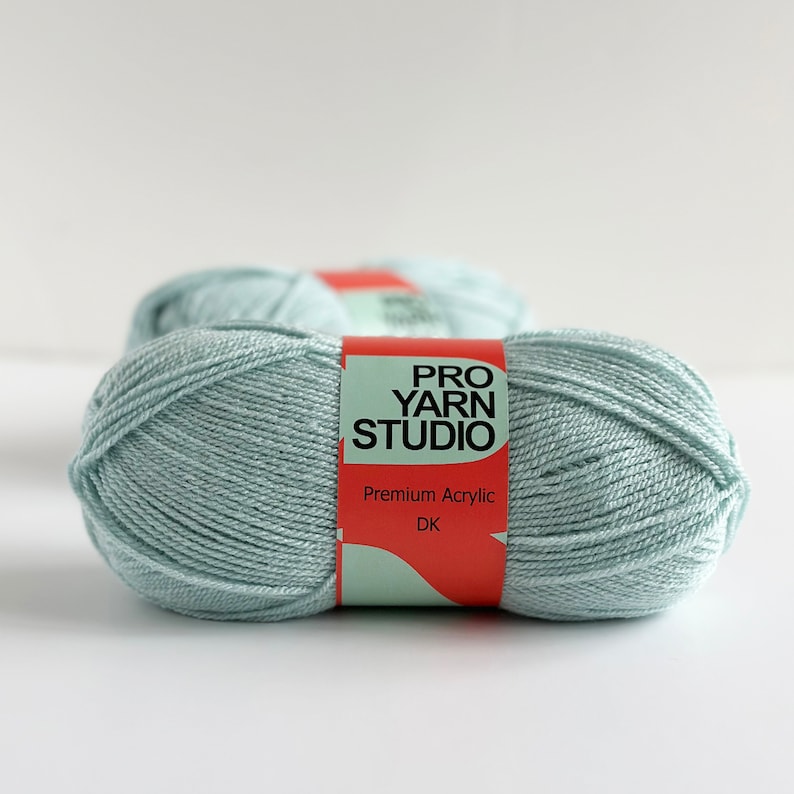 K&ouml;nnte beinhalten: Zwei Kn&auml;uel hellblaues Garn mit der Aufschrift "PRO YARN STUDIO Premium Acrylic DK".