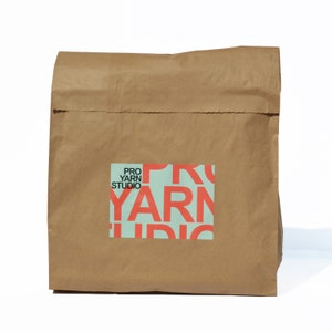 May include: A brown paper bag with a logo that says "Pro Yarn Studio" in red letters on a light blue background.