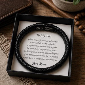May include: A black braided leather bracelet with a matte black metal clasp featuring an infinity symbol and the text "Love you forever". The bracelet rests on a white card inside a black box, printed with the message "To My Son" and a poem.