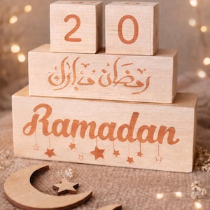 Op de afbeelding: Houten Ramadan decoratieset. Inclusief blokken met de cijfers 2 en 0, Arabisch schrift en het woord "Ramadan" met steraccenten. Voorzien van maan- en steruitsparingen. De set is gemaakt van lichtgekleurd hout.