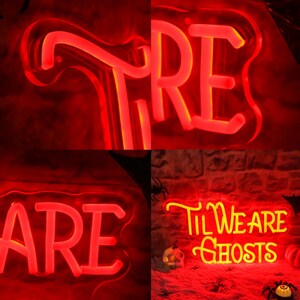 May include: Four neon signs with the words "Till We Are Ghosts", "Are", "Fire" and "Till We Are Ghosts" in yellow and red. The signs are lit up and have a glow around them.