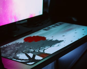 May include: A black desk with a pink and white computer monitor and a mouse pad with a black and white tree design. The mouse pad has a red accent.