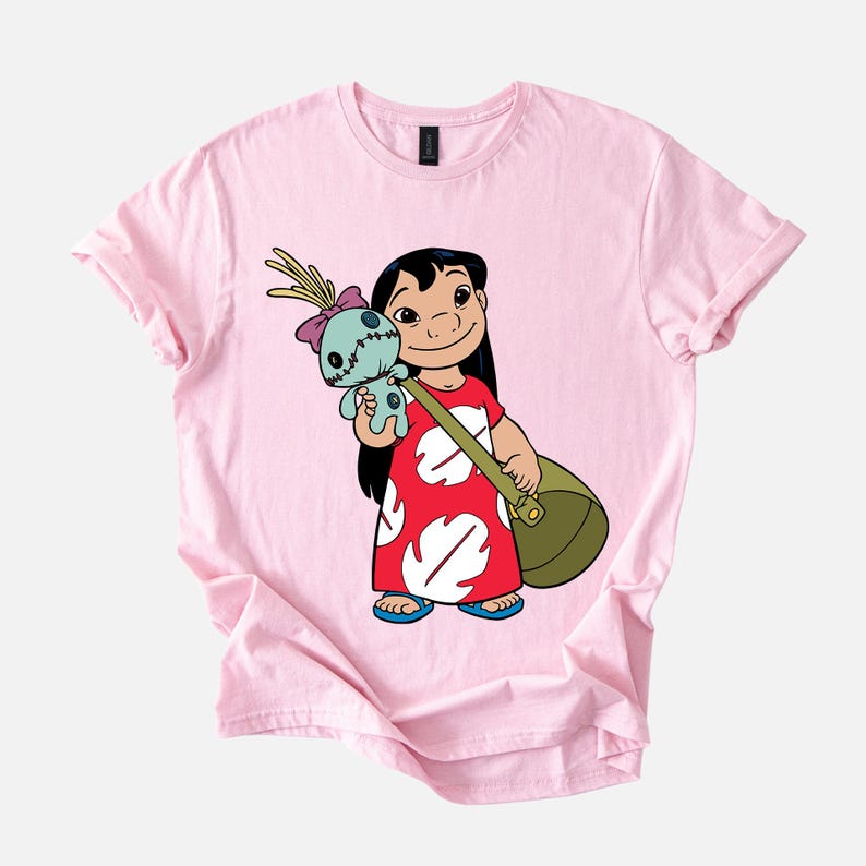 Puede incluir: Camiseta rosa claro con una ilustraci&oacute;n de dibujos animados de una ni&ntilde;a sosteniendo una mu&ntilde;eca y una bolsa verde. La ni&ntilde;a lleva un vestido rojo con estampados de hojas blancas y sandalias azules. La mu&ntilde;eca es azul con un lazo rosa.