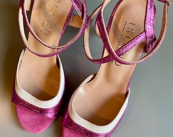 May include: Pair of pink metallic open-toe sandals with ankle straps. The sandals have a white trim around the toe and a small heel. The brand name "ISLAND LONDON" is visible on the insole.