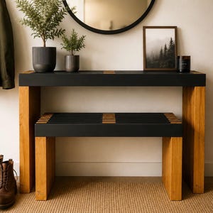 Op de afbeelding: Een rechthoekige sidetable en een bijpassende bank, beide met een matzwart oppervlak en poten van natuurlijk hout. De zitting van de bank bestaat uit zwarte latten met houten accenten, en het tafelblad heeft vergelijkbare houten details.