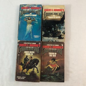 May include: Four vintage paperback books by Robert E. Howard, featuring the character Cormac Mac Art. The covers display illustrations of action scenes and fantasy figures. Titles include "The Mists of Doom" and "Tigers of the Sea."