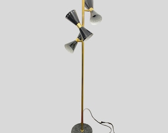 Può includere: Lampada da terra vintage con asta dorata e paralumi neri e dorati. La lampada ha una base in marmo e un cavo di alimentazione nero. I paralumi sono a forma di cono e puntano in direzioni diverse.